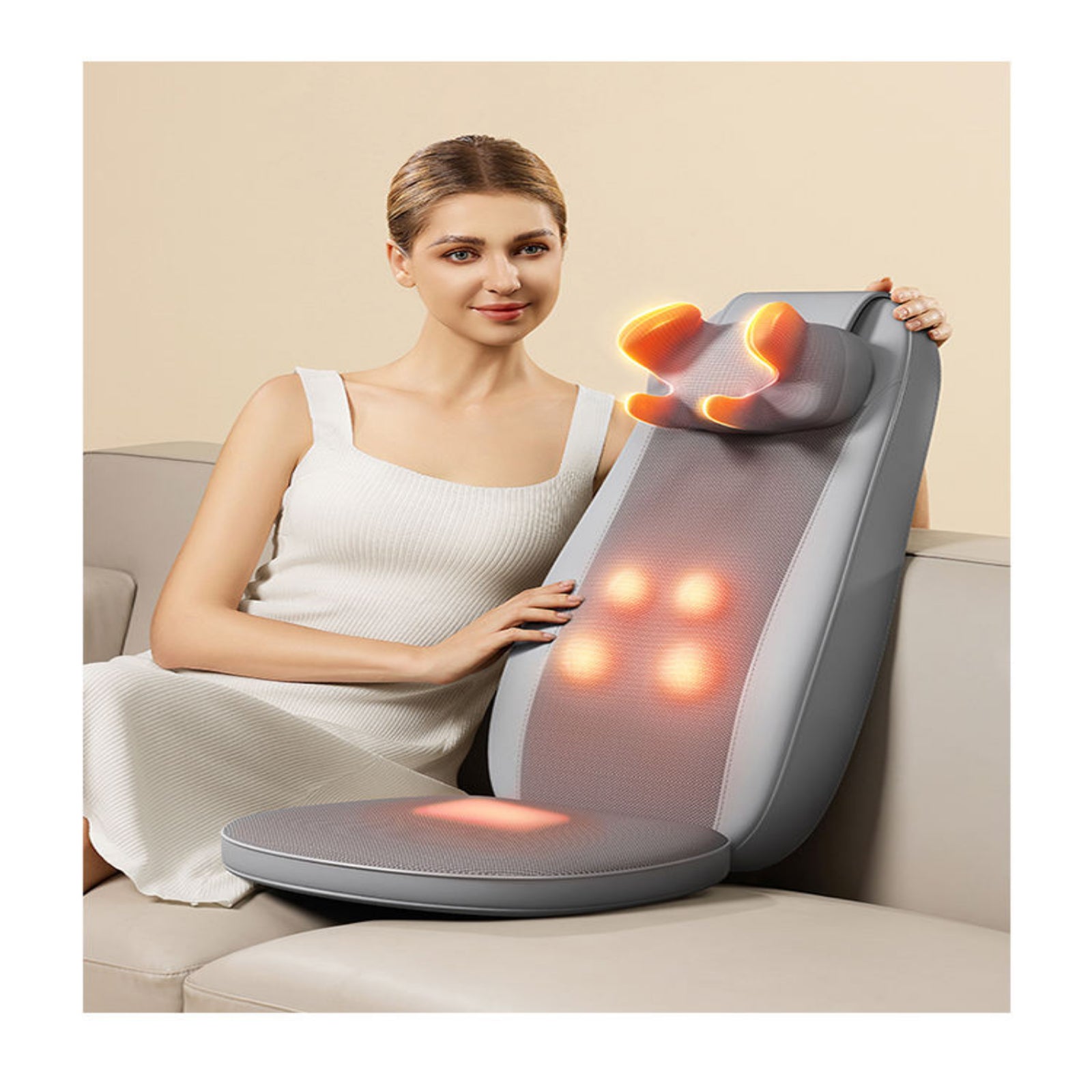 Woman using a massage pillow on a couch with a beige background